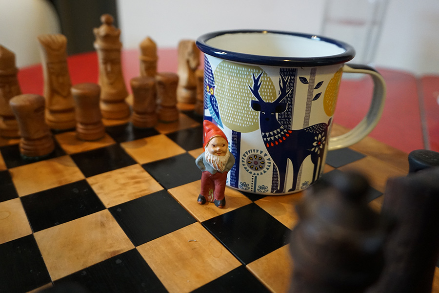photo of a garden gnome on a chess set with a coffee cup with a deer drawing on it. British Columbia, Canada