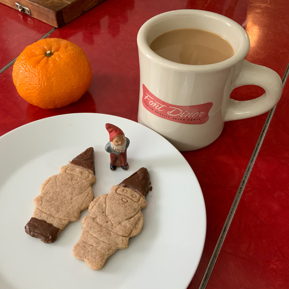 Photo of a coffee cup and cookies shaped like a gnome.