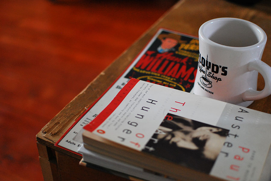 photo of coffee cup, books and music poster of Hank Williams.