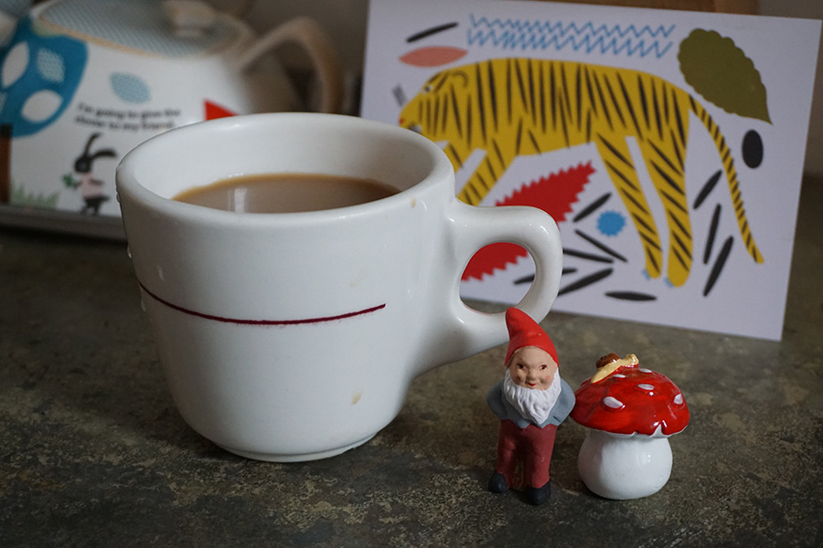 Photo of a tiny gnome next to a coffee cup.